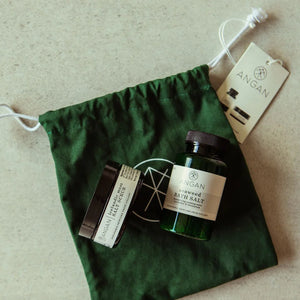 Bath products including a jar and a bottle on a green drawstring bag with 'ANGAN' branding.