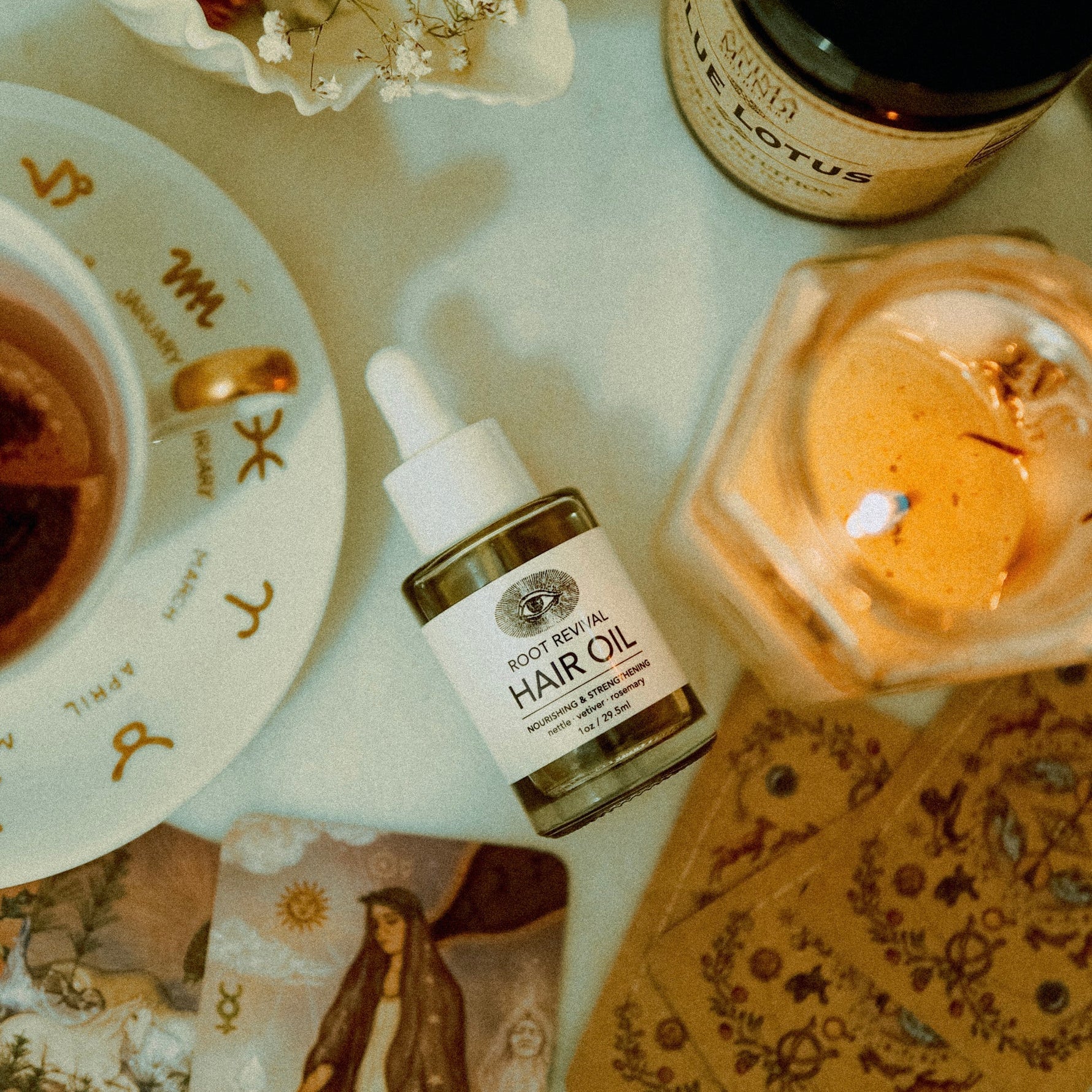 Hair oil bottle, tarot cards, and tea on a table with a candle