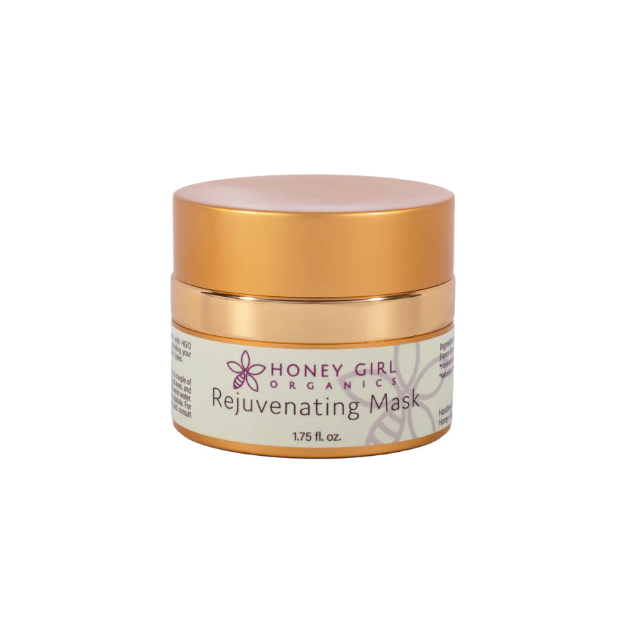 A jar of Honey Girl Organics Rejuvenating Mask, with a gold and white color scheme and a label that includes the product name and branding.