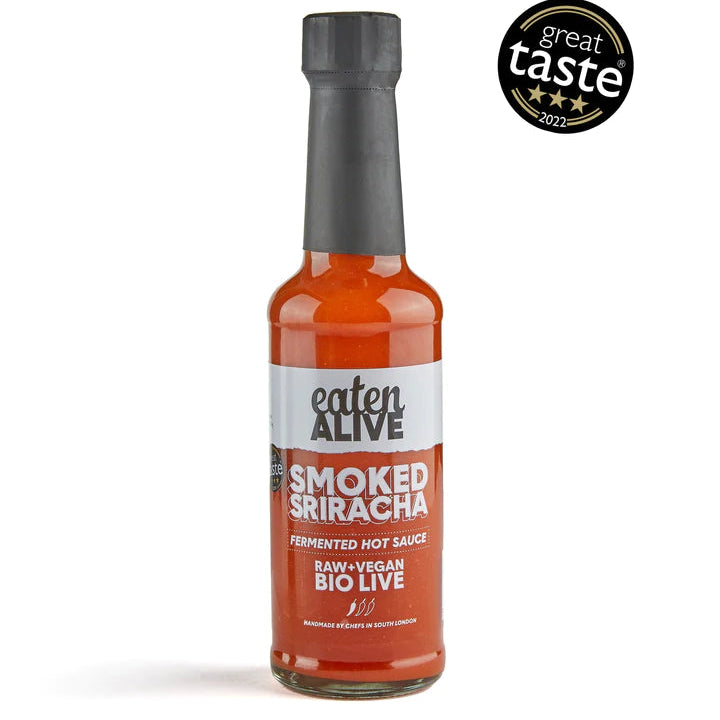 A bottle of Eaten Alive Smoked Sriracha Hot Sauce with a label that includes the brand name and product description. The sauce appears to be in a clear glass bottle with a black cap.