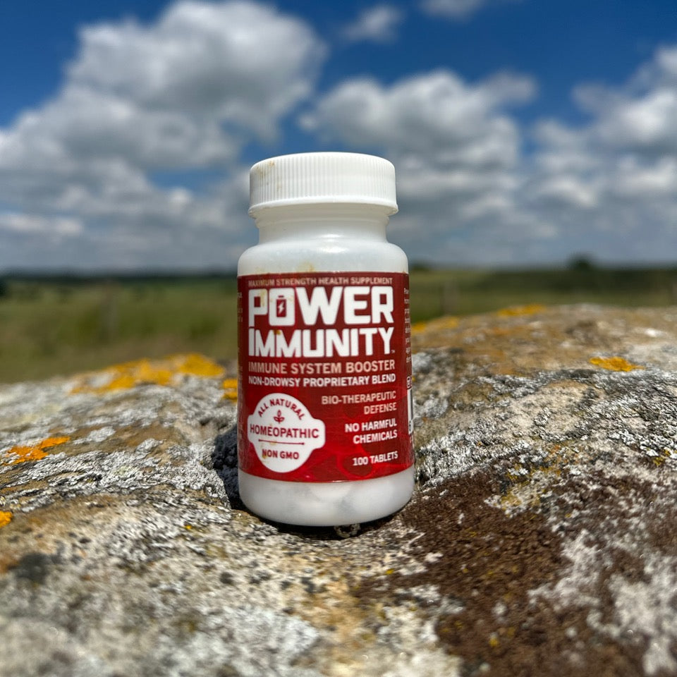Bottle of Power Immunity supplement on a rocky surface with a cloudy sky background