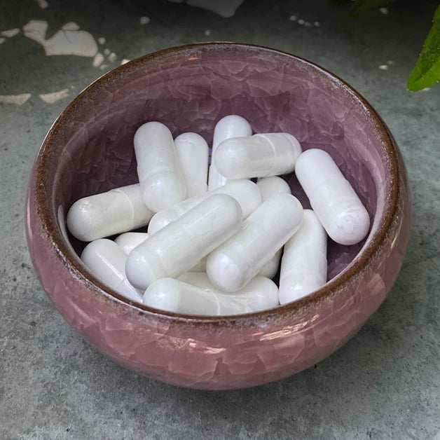 Dragon Herbs Pearl capsules in a small pink bowl