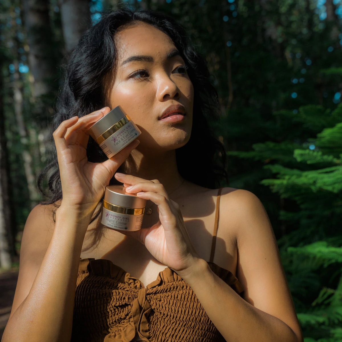 Woman holding a jar of Honey Girl Organics Face & Eye Crème Extra Sensitive to her cheek
