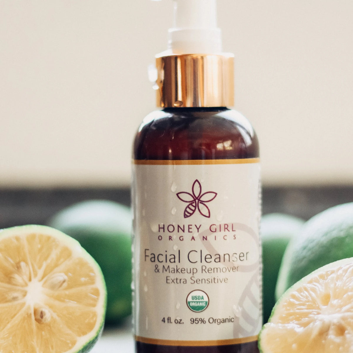 Bottle of Honey Girl Organics Facial Cleanser & Makeup Remover Extra Sensitive with halved limes