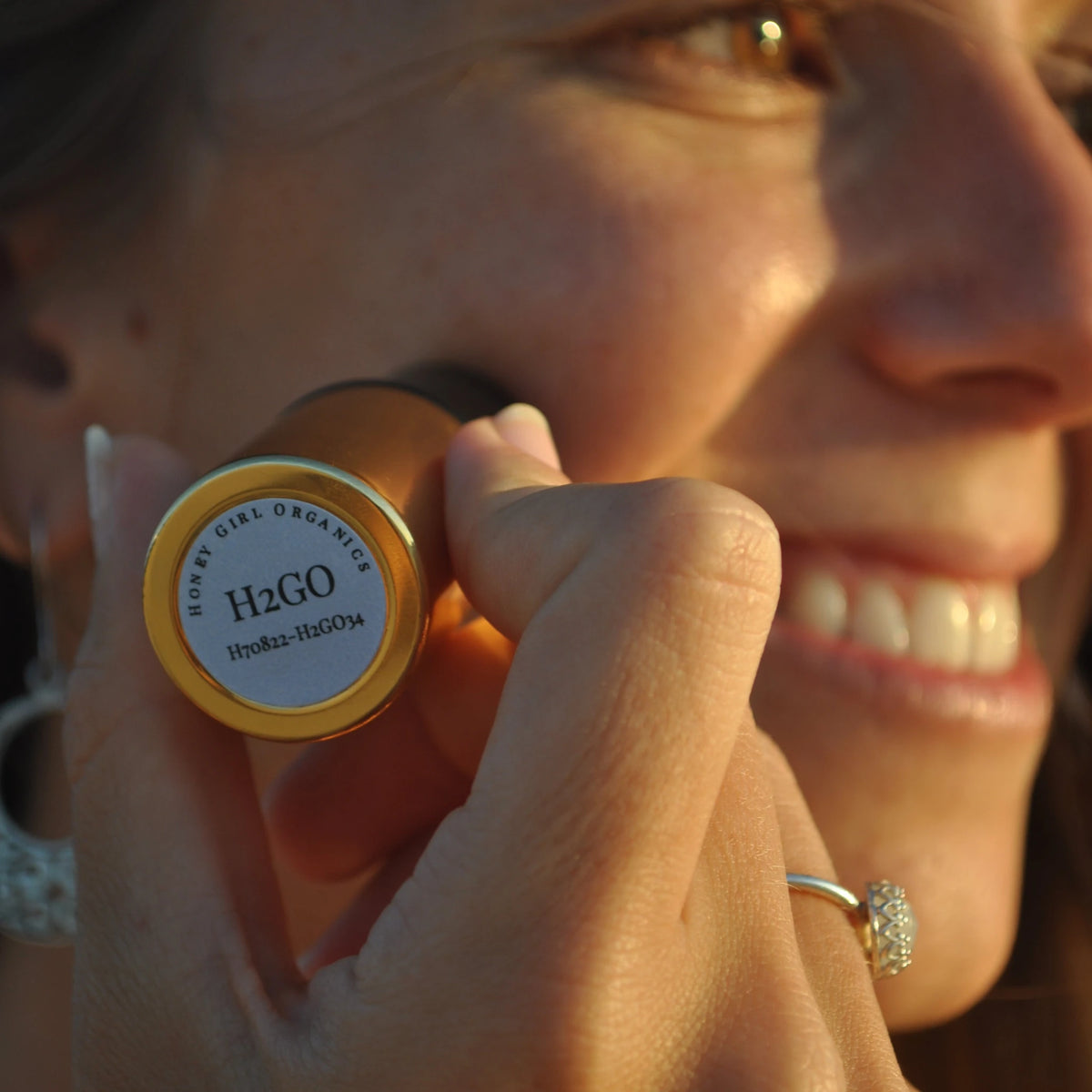 Woman smiling while applying a Honey Girl Organics H2GO stick to her cheek