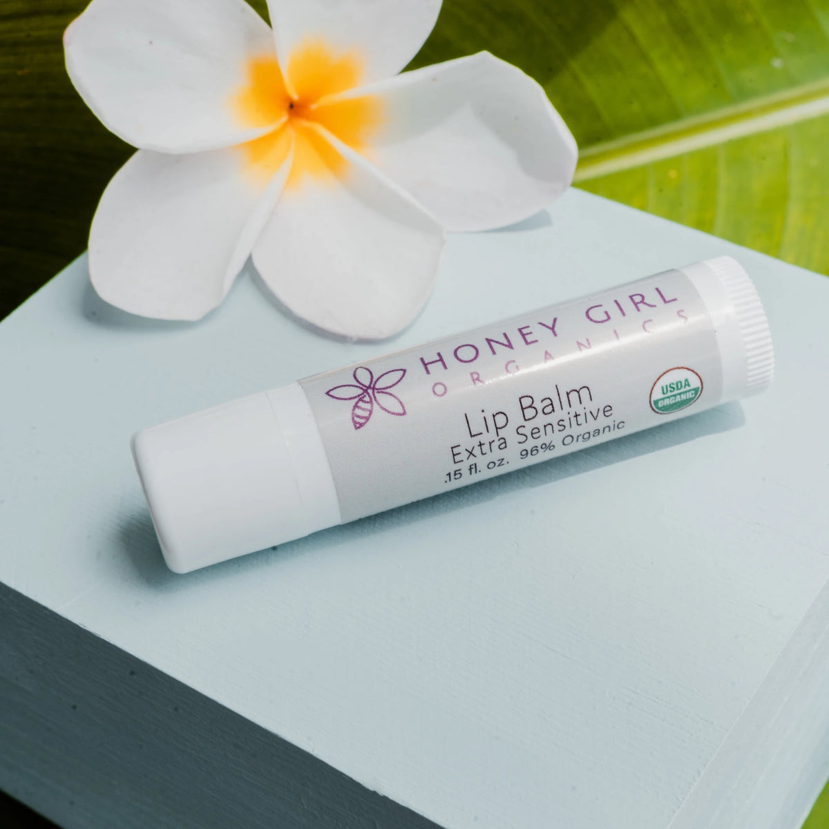 Honey Girl Organics Lip Balm Stick Extra Sensitive with a frangipani flower